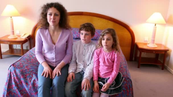 Matka i jej dzieci chłopiec i dziewczynka siedzieć na kanapie i klaskać w ręce Kiedy oglądać tv — Wideo stockowe