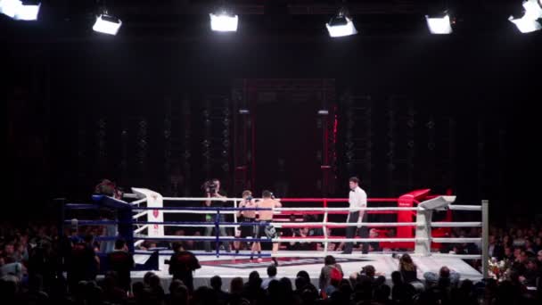 Deux athlètes se battent sur le ring de boxe dans une grande salle sombre à la bataille de Moscou 3 — Video