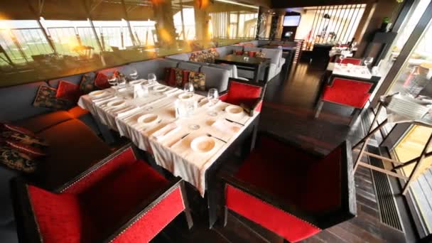 Декорований стіл зі скляним посудом стоїть у залі ресторану поруч з терасою — стокове відео