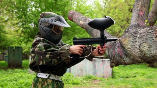 Jongen in camouflage staan in positie schieten en brengen paintball pistool op vertakking van de beslissingsstructuur — Stockvideo