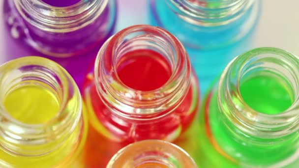 Six bouteilles ouvertes transparentes tourne avec de l'huile de couleur sur eux 