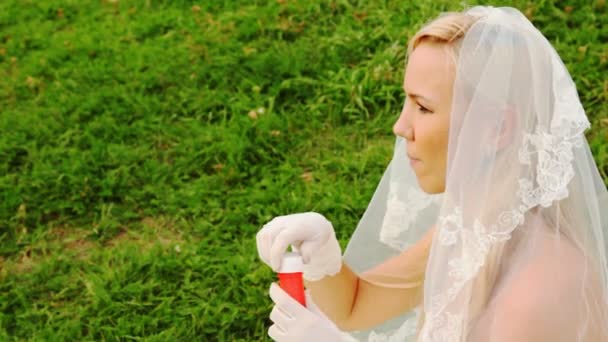 Bride in white starts up soap bubbles on meadow — Stock Video