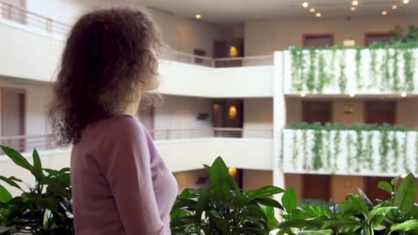 Žena stojí na balkóně s rostlinami v několika podlažích — Stock video