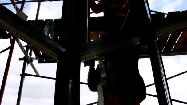 Silhouetten von Arbeitern sind hinter Glas auf einem Gerüst zu sehen — Stockvideo