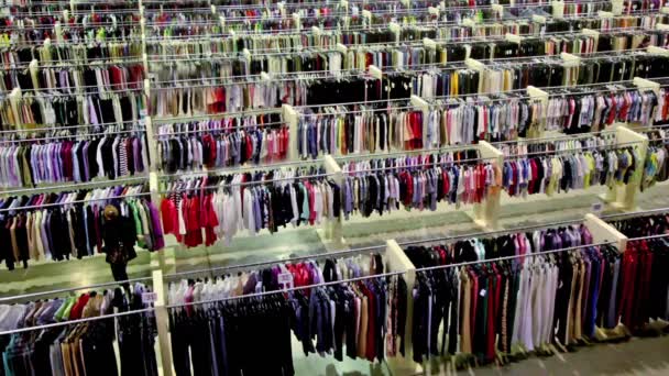 En kvinna titta varor bland massa kläder i butik — Stockvideo