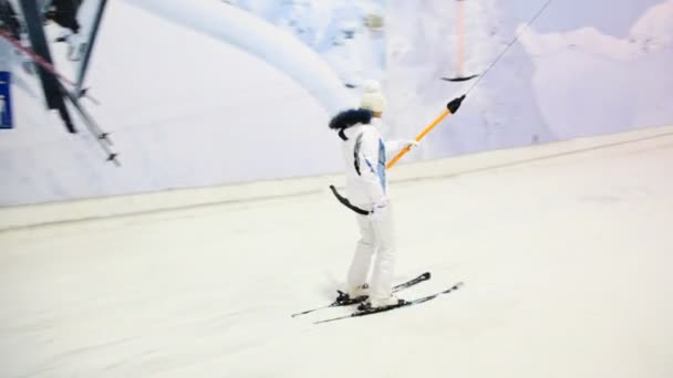 Skier girl sitting on handle goes up hill in winter sport center — Stock Video