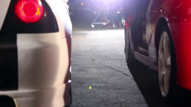 Dua mobil dengan desain olahraga berwarna-warni dalam cahaya proyektor di malam hari — Stok Video
