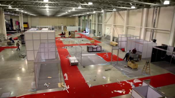 Plusieurs travailleurs retirent les stands dans le hangar d'exposition — Video