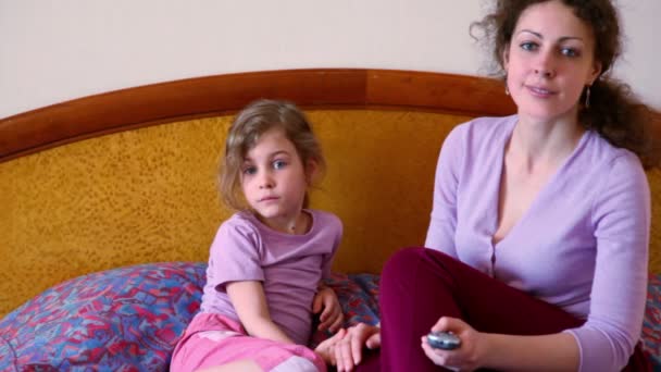 Матері і малою донькою сидіти на ліжко і дивитися телевізор — стокове відео