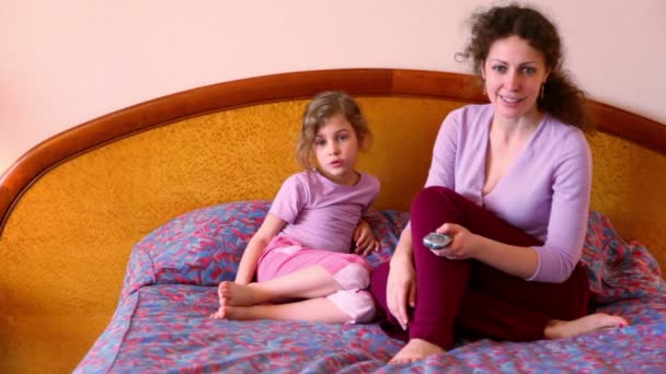 Anne ve kızı yatağa otur ve Uzaktan kumanda ile tv izlemek — Stok video