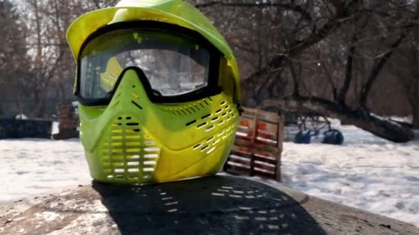 Желтый шлем для пейнтбола лежал на фоне детской площадки — стоковое видео