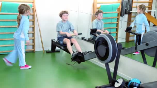 Dos niños entrenan en el gimnasio, el equipo de entrenamiento del niño y la niña pequeña saltan cerca — Vídeo de stock