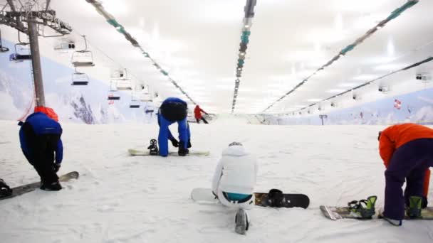 Professional sportsmans with snowboard prepares for training in indoor ski — Stock Video