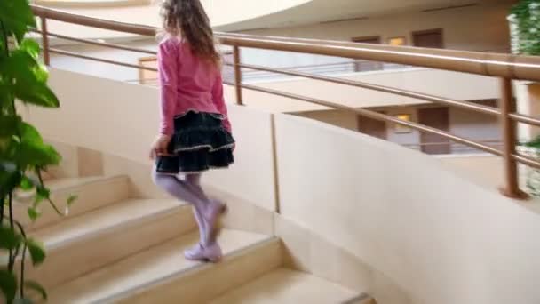Petite fille marche à l'étage par escalier circulaire dans un immeuble à étages multiples — Video