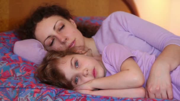 Мать и дочь спят в постели, а потом просыпаются и мама целует девочку — стоковое видео