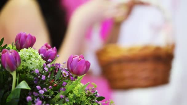 Ramo de flores en la espalda y desenfoque niña sosteniendo cesta de ramitas — Vídeo de stock