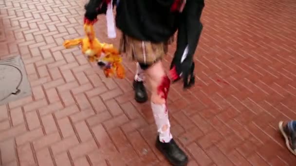Chica camina por el pavimento con las piernas ensangrentadas y lleva juguete suave — Vídeos de Stock