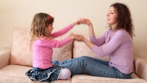 Mutter und ihre kleine Tochter sitzen auf dem Sofa und spielen Händeklatsch — Stockvideo