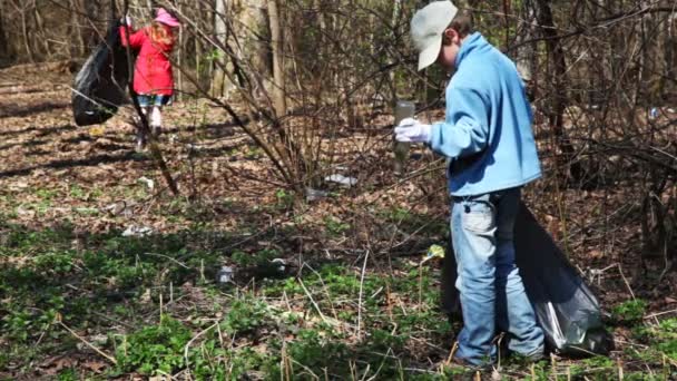 Fiú és lány a fekete táskák tisztítani természet, gyűjtsük össze szemetet park — Stock videók