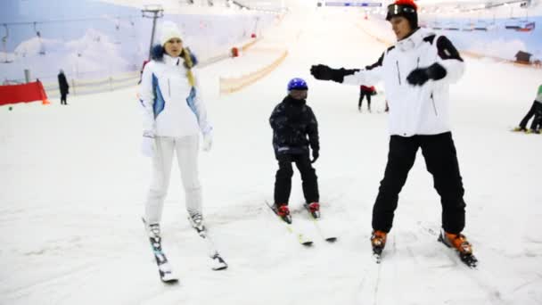 Instructor shows girl and little boy some exercises on skis — Stockvideo