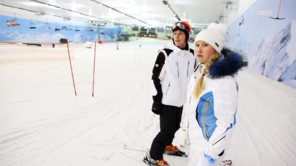 Instruktor mit Mädchen wartet, bis andere Leute zum Skifahren auf die Piste gehen und dann selbst losfahren — Stockvideo