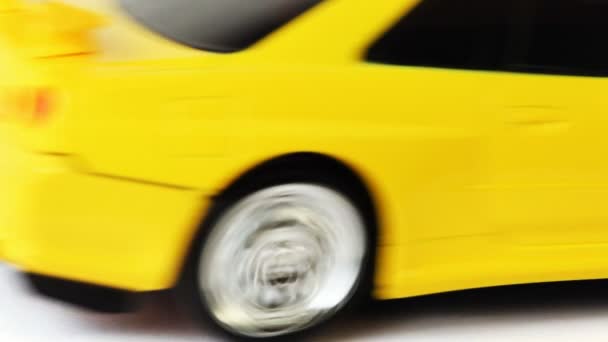 Yellow toy radio-controlled car moves back and forth on white background — Stock Video