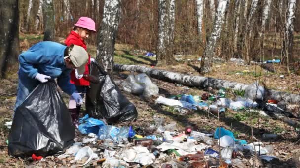 Niño y niña con bolsas negras recogen mucha basura en el parque — Vídeos de Stock