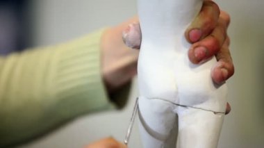 heykeltraş kadın heykelcik tutar ve bacakları dosyası tarafından parlatır