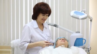 güzellik uzmanı galvanotherapy yüzünde istemciye yapar.