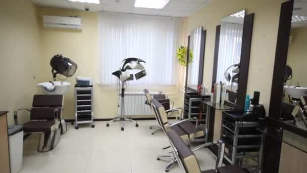 Flying motion of camera in salon hairdressing salon along armchairs to window — Stock Video