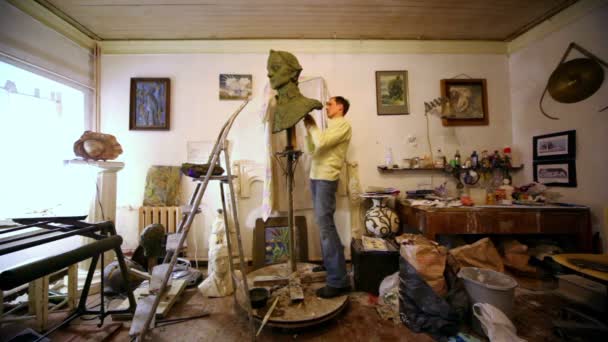 Sculptor maakt A.Suvorov buste onder bugs, emmer en andere spullen liggen rond in de studio — Stockvideo