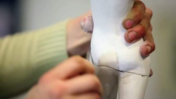 Sculptor holds female figurine and polishes its legs by file — Stock Video