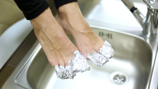 Los dedos de la mujer se envuelven en papel de aluminio para hacer la corrección de las uñas por encima del lavabo — Vídeo de stock