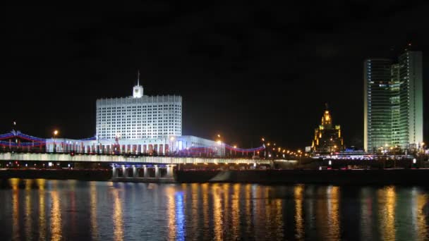 Белый дом стоит за мостом в свете ночных фонарей — стоковое видео