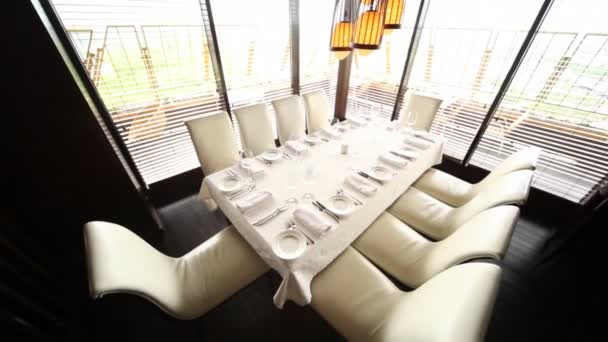 Table for ten persons stands in corner of hall of restaurant near to windows with view on terrace — Stock Video