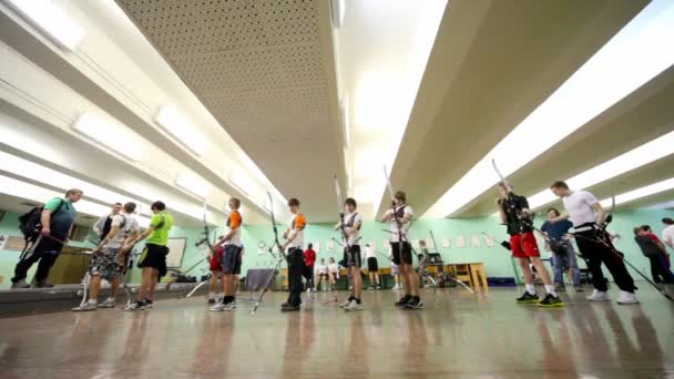 Viele Schüler-Bogenschützen stehen beim traditionellen Bogenschießturnier im Schießstand — Stockvideo
