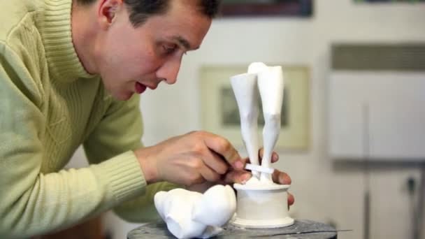 Скульптор с папочкой исправляет ноги незавершенной женской фигурки — стоковое видео