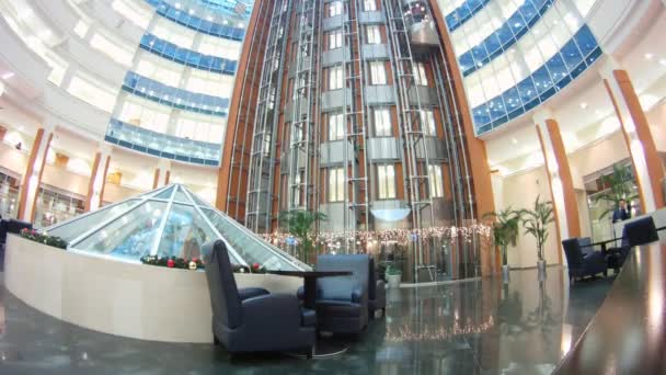 In der Halle des Business-Centers gehen Aufzüge nach oben und unten und gehen die Menschen — Stockvideo
