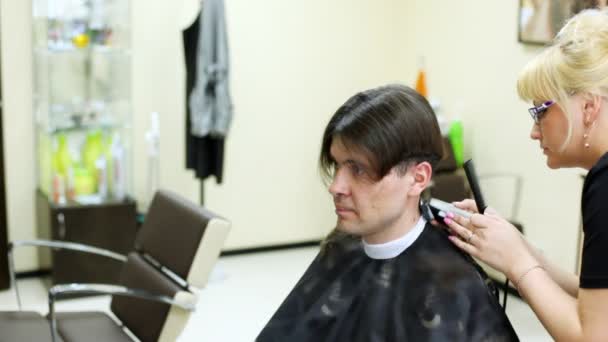 Friseur schneidet Mann mit langen Haaren per Haarschneidemaschine Haare am Nacken — Stockvideo