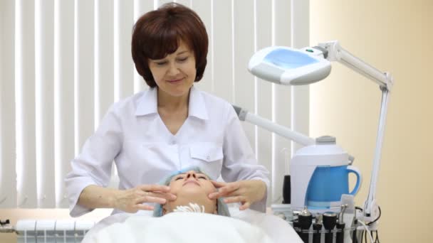 Mulher recebe massagem facial no salão de beleza de esteticista — Vídeo de Stock