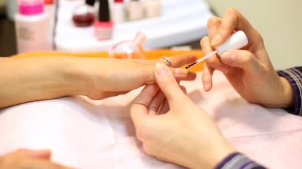 Cosmetician colors nails of woman its fingers are decorated by rings — Stock Video
