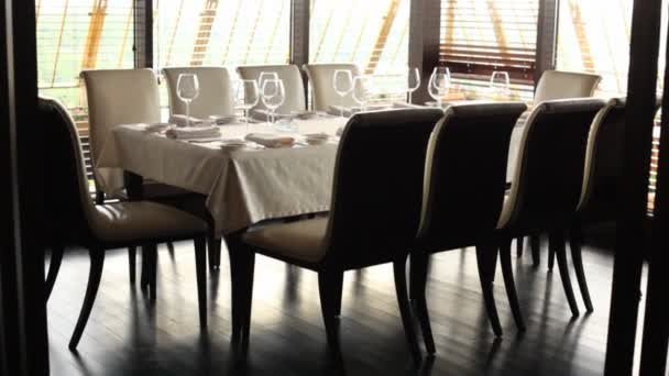 Chandelier with four yellow lamps hangs over table for ten persons — Stock Video