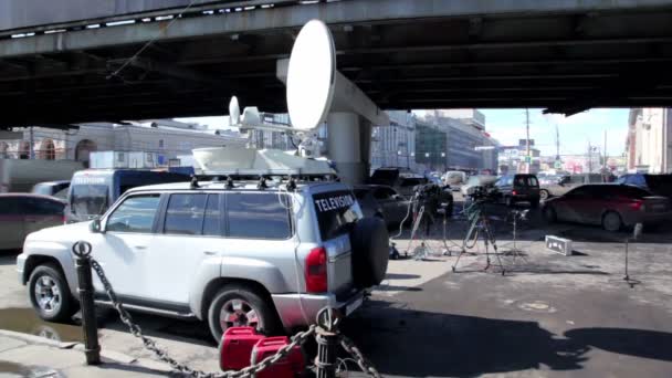 Samochód z anteny satelitarne na dachu i innych urządzeń tv w pobliżu na tle ruchu miejskim — Wideo stockowe