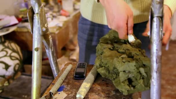 Sculptor picks clay with knife, cell phone lay near — Stock Video