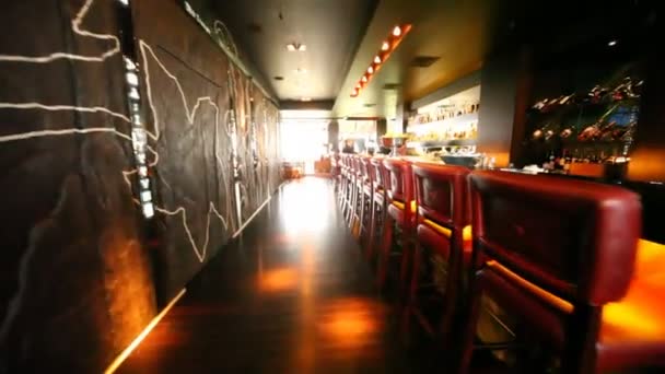 Chairs in bar stand along long bar counter where there are two women working in restaurant — Stock Video