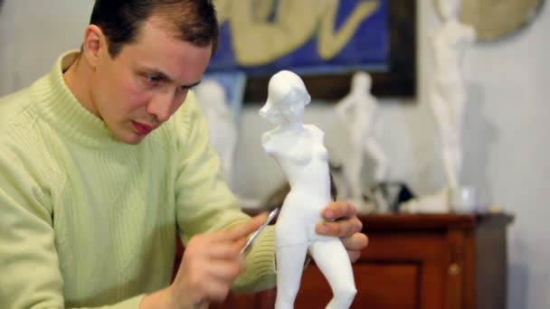 Skulptör puts kvinnliga statyett av filen på bakgrund av andra statyetter — Stockvideo