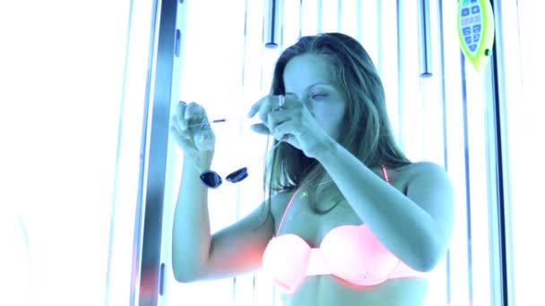 Young woman stand in solarium and sunbathes in salon — Stock Video