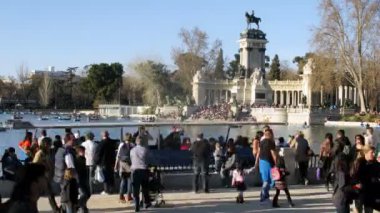 Tourists walk on embankment near memorial to king Alphonse XII