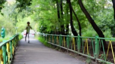Ağaçların altında yoluyla scooter üzerinde küçük kız rides