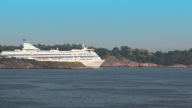 büyük kruvazör helsinki yakınındaki kıyı ormanla yanında yüzüyor.